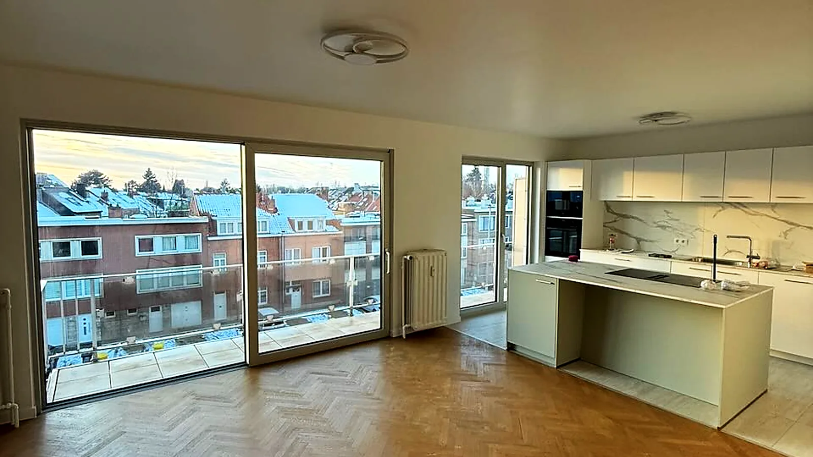 Grande baie coulissante à profilé noir ouvrant un séjour lumineux sur une terrasse, avec cuisine ouverte — réalisation Pulsar Windows