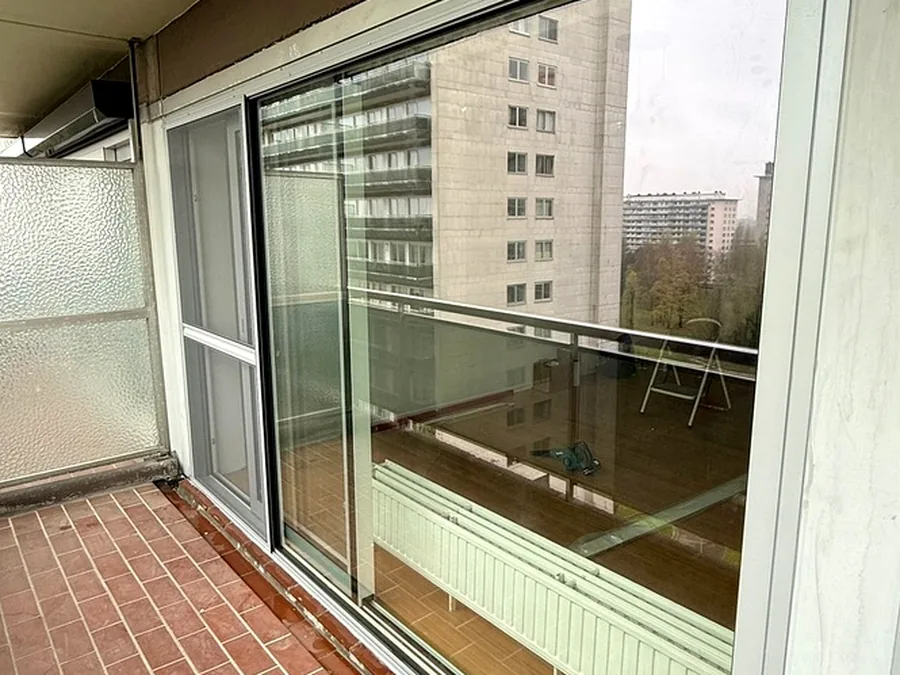 Baie coulissante à profilé blanc sur un balcon carrelé d’appartement — réalisation Pulsar Windows