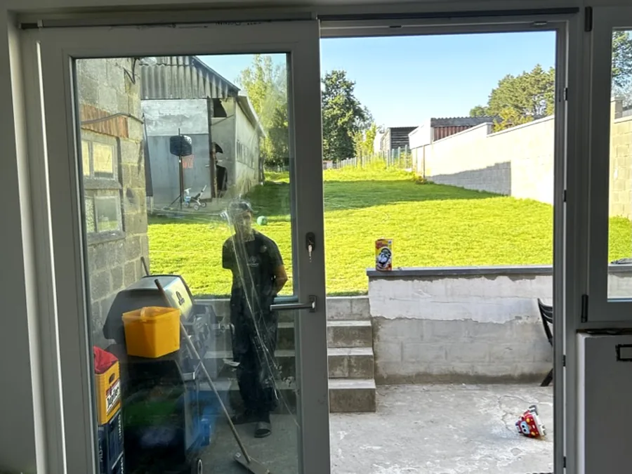 Baie coulissante à profilé blanc vue de l’intérieur, ouvrant sur le jardin — réalisation Pulsar Windows