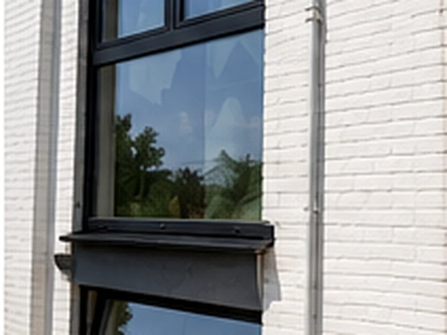 Fenêtre à cadre sombre installée sur une façade en briques claires.