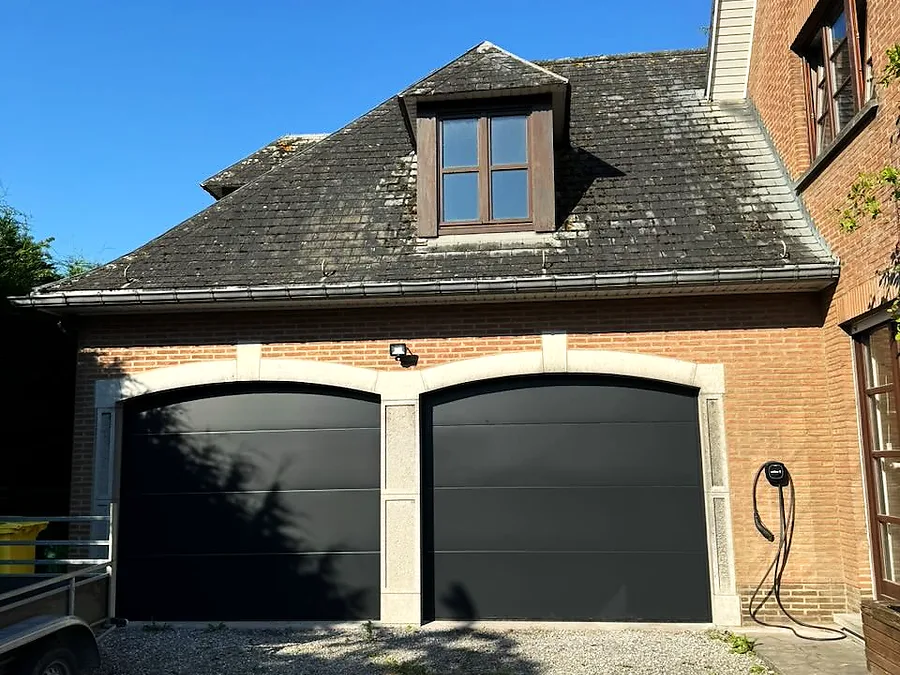 Double porte de garage sectionnelle anthracite sur une maison en briques, avec lucarne — réalisation Pulsar Windows