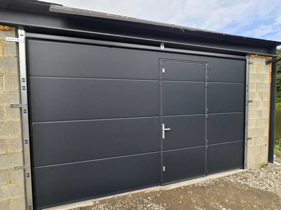 Porte de garage sectionnelle anthracite avec portillon — réalisation Pulsar Windows