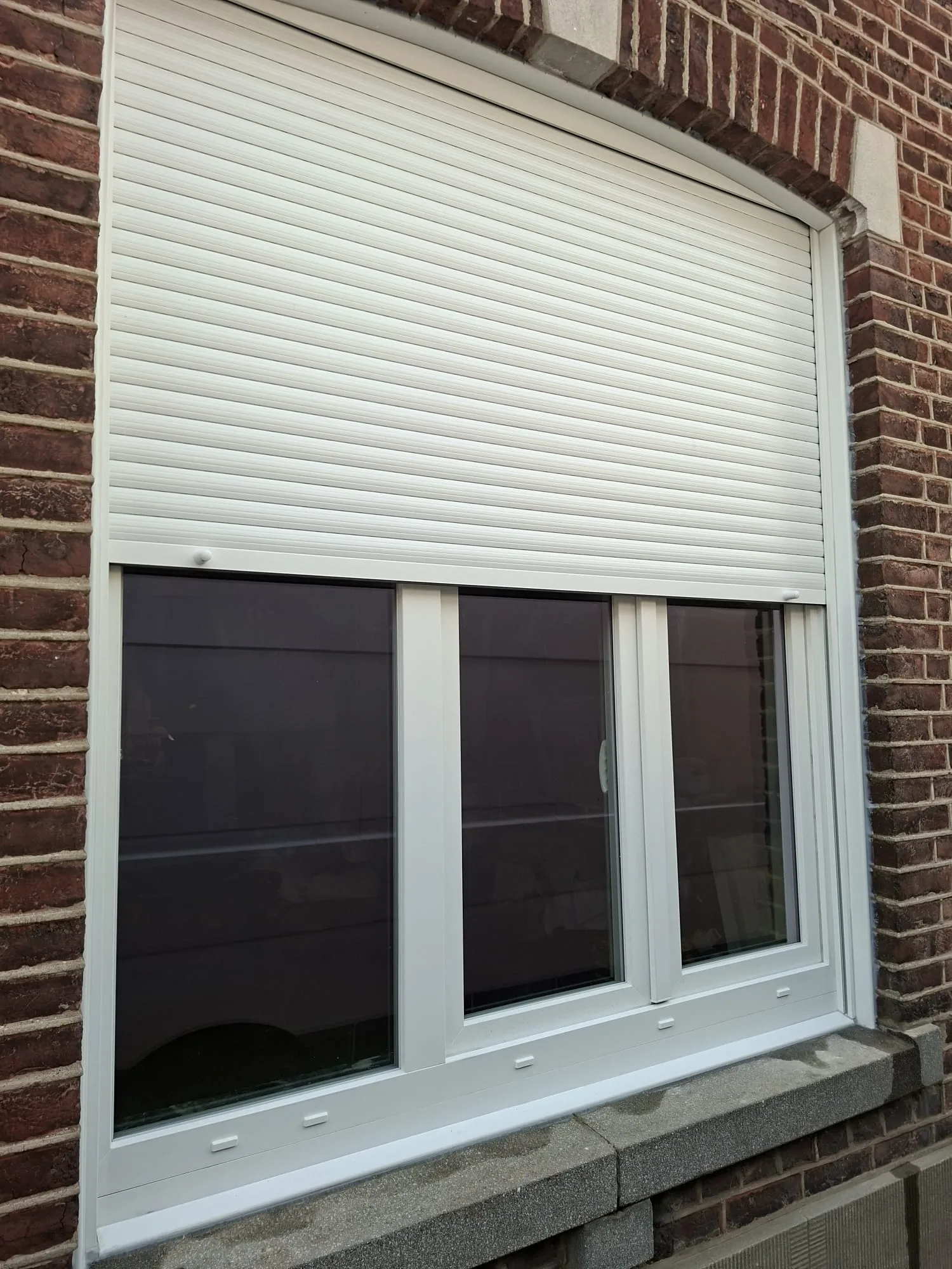 Grande fenêtre PVC blanche avec volet roulant, coffre logé dans le jour de la fenêtre au-dessus de la baie