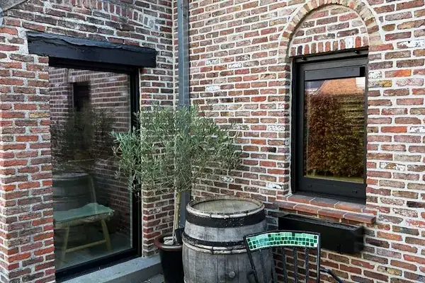 Fenêtres à profilé noir sur une maison en briques rénovée, avec terrasse — réalisation Pulsar Windows
